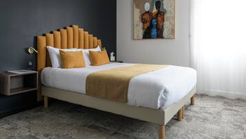 Quarto moderno com cama, mesa de cabeceira, uma obra de arte na parede e piso coberto por carpete.