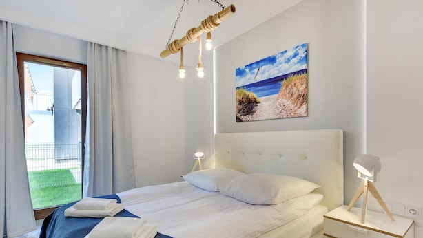 Hotelkamer met een bed, nachtkastjes, een strandschilderij en uitzicht op het omliggende landschap.