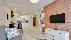 Een moderne woonkamer met een grijze bank, een glazen salontafel en een accentmuur van baksteen.