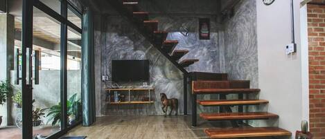 A modern interior with a staircase, a television, and a horse statue.