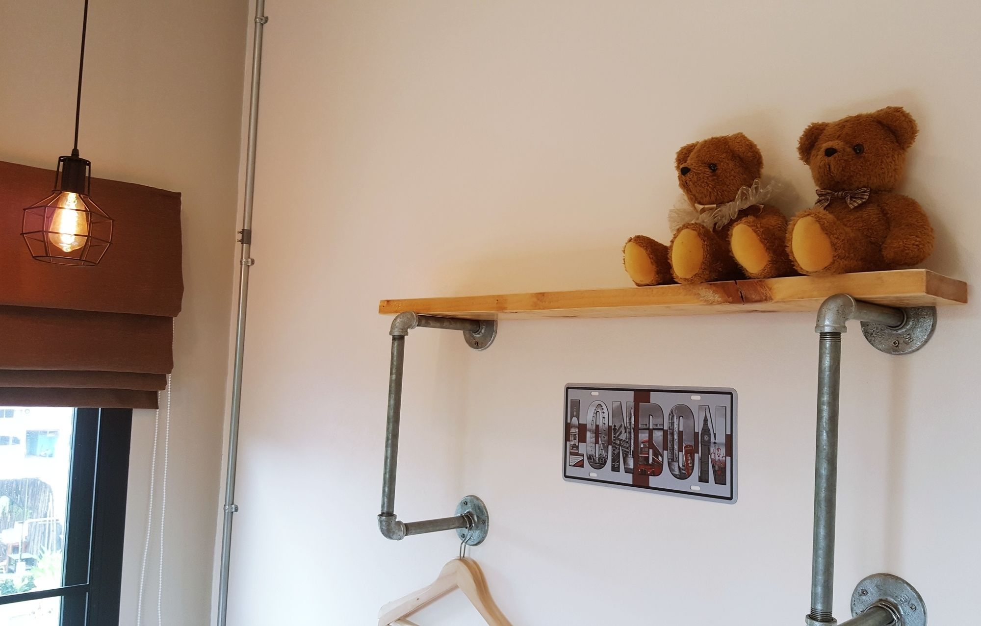 Ein Regal mit zwei Teddybären und einem Poster an einer weißen Wand.