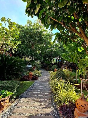 A garden pathway with various plants and a stone walkway. - Baan Canalee (Ayutthaya)