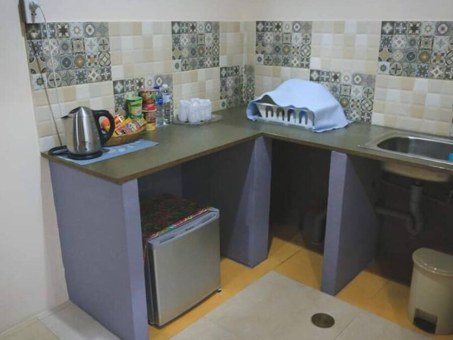 A compact kitchen with a refrigerator, sink, and tiled backsplash.