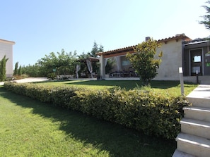 A residential property with a well-maintained lawn, a patio area with outdoor furniture, and a covered outdoor space.