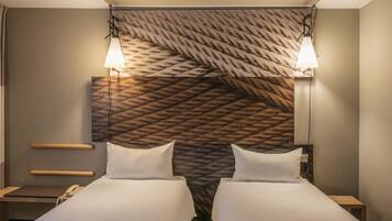 A hotel room with two beds, a headboard with a textured pattern, bedside lamps, a telephone, and a small wooden table.