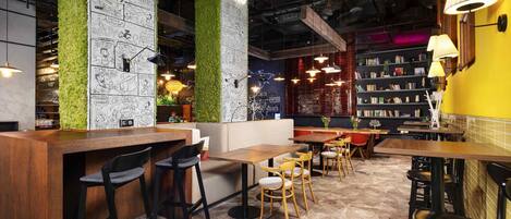 A restaurant interior with high ceilings, exposed beams, green vertical gardens, and a variety of seating arrangements.