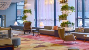 A modern hotel lobby with a geometric patterned carpet, comfortable seating, and large windows with curtains. - ibis Poznan Centrum (Poznan)