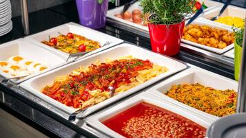 Un buffet proposant divers plats, notamment des pâtes, des œufs et des haricots.
