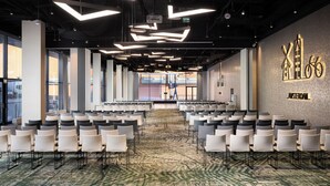 A conference room with rows of white chairs, a patterned carpet, and modern lighting fixtures. - ibis Poznan Centrum (Poznan)