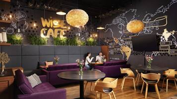 A modern cafe interior with a sofa, round tables, wooden chairs, and a world map on the wall.