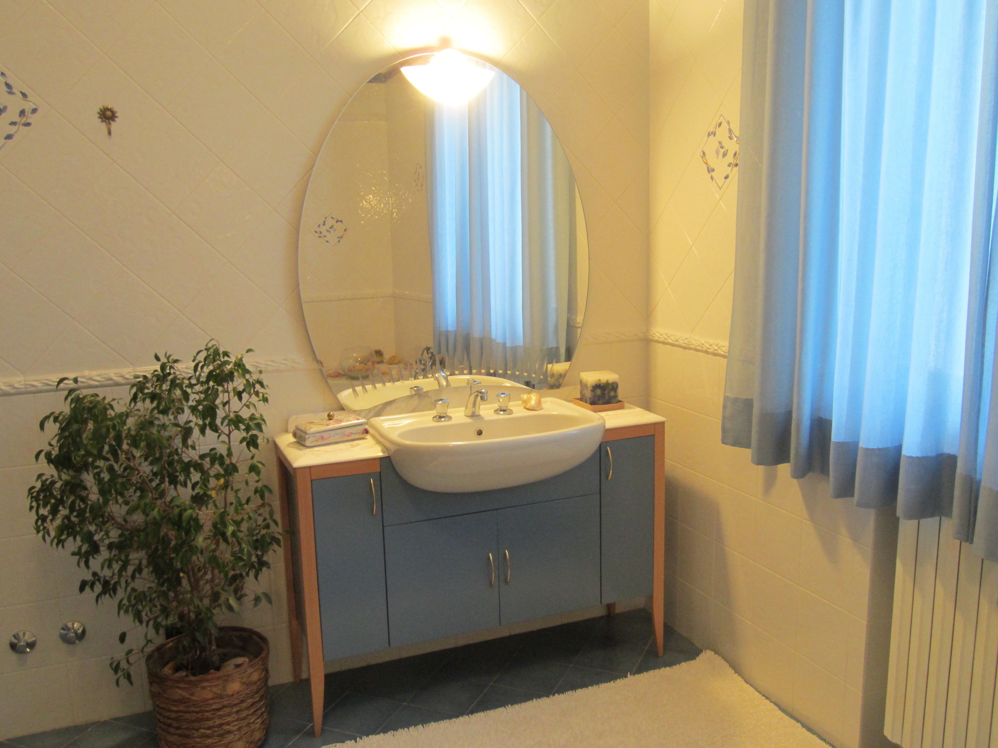A bathroom with a sink, mirror, and potted plant.