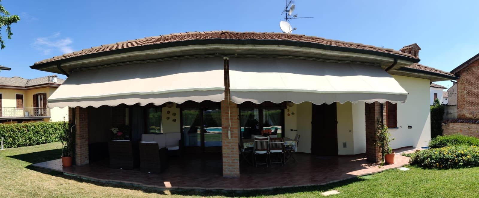 Ein Haus mit überdachter Terrasse, einem Ziegelkamin und einer Satellitenschüssel.