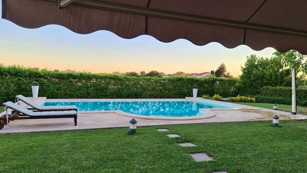 A swimming pool with a covered area, lounge chairs, and a well-maintained lawn. - Marinella B (Cornale e Bastida)
