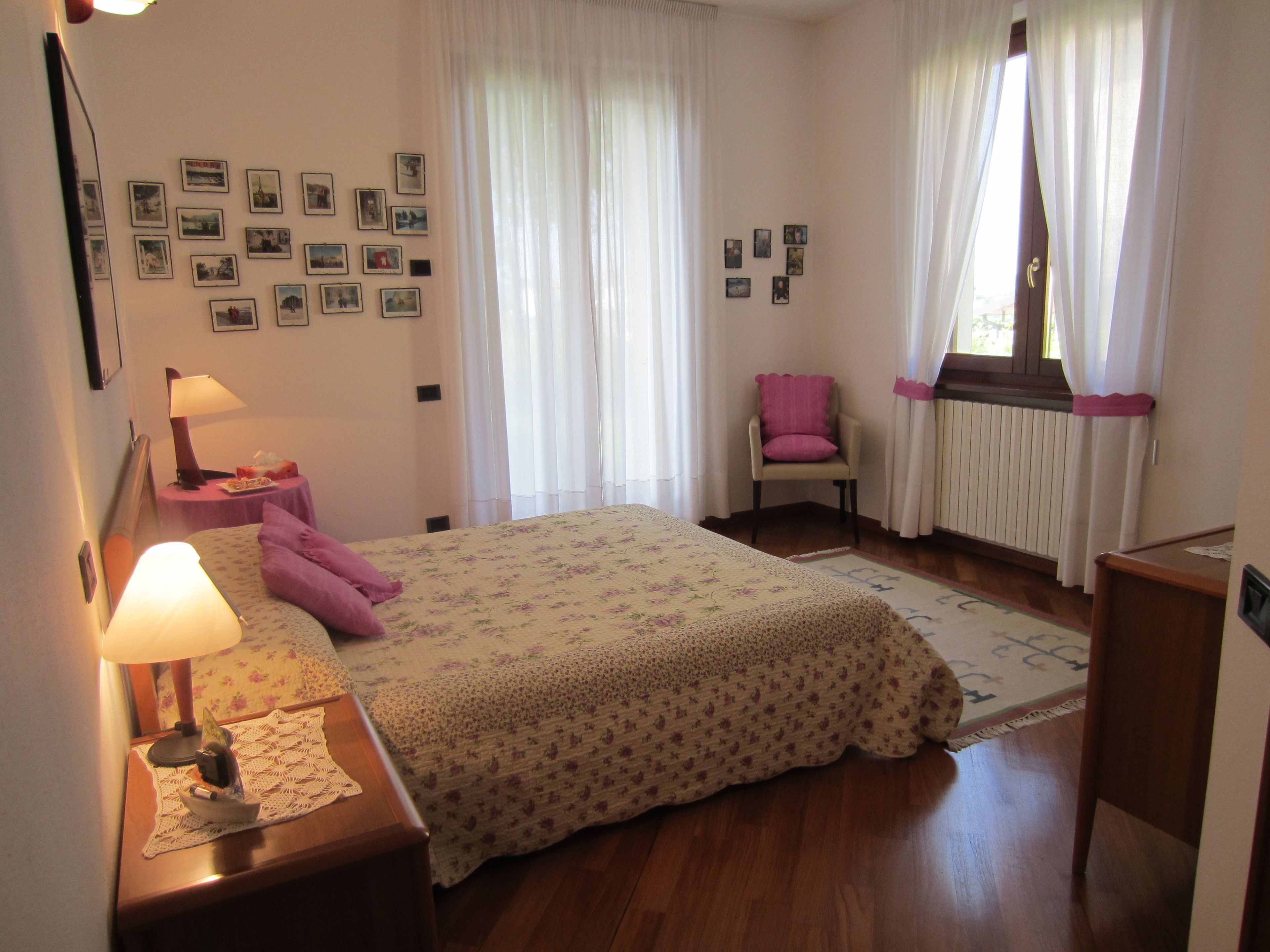 Ein Schlafzimmer mit einem Bett, einem Sessel, einem Tisch mit Lampe und Bildern an der Wand.