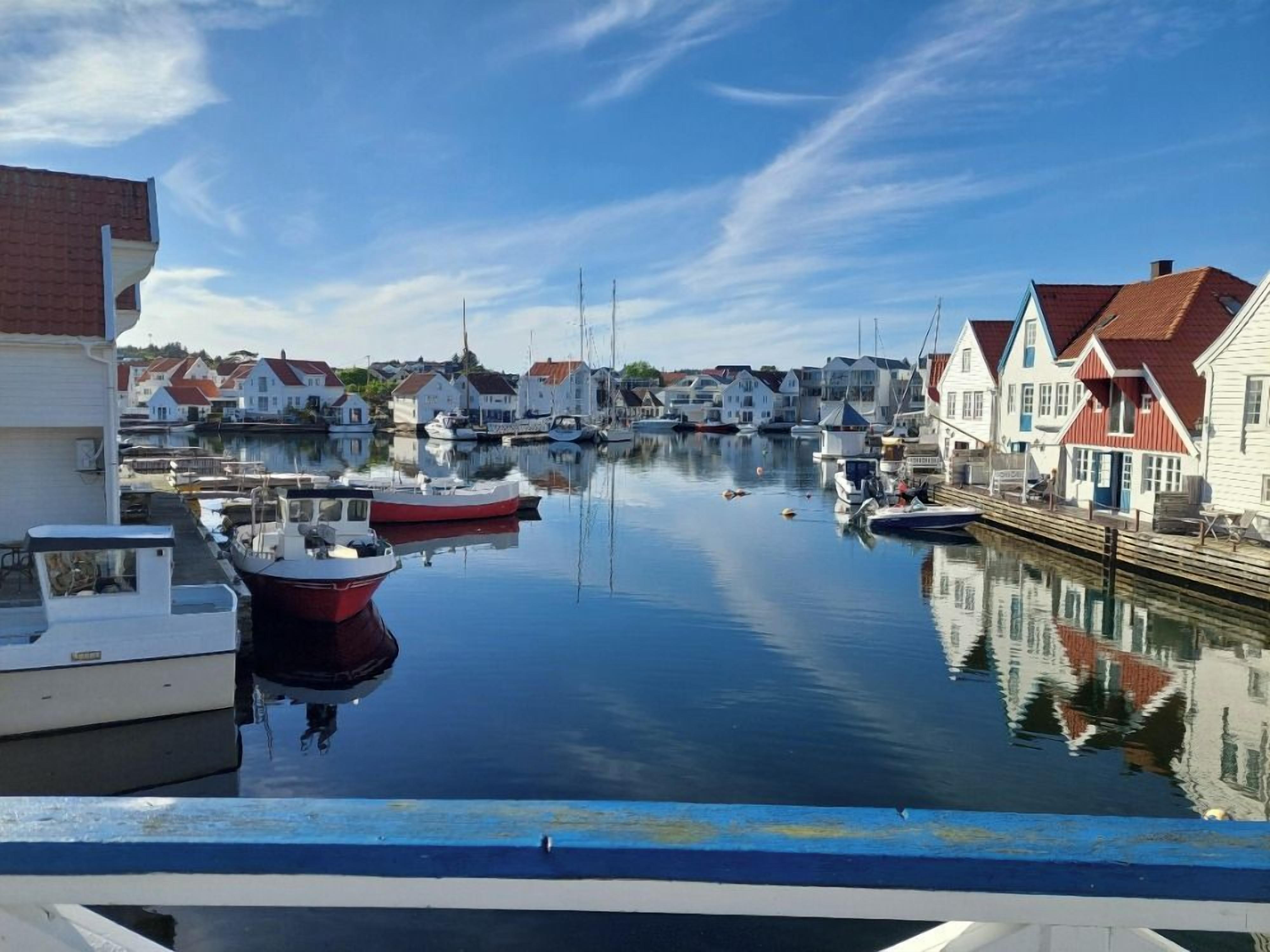 A marina with boats docked, waterfront houses, and a clear sky.