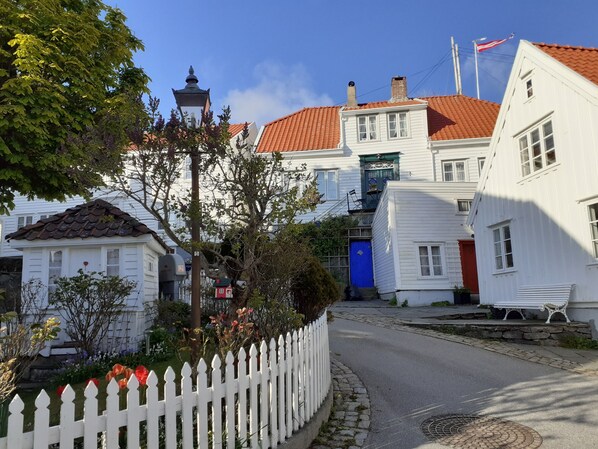 A street view with white buildings, a blue door, and a white picket fence. - Skudenes Camping (Karmoy)