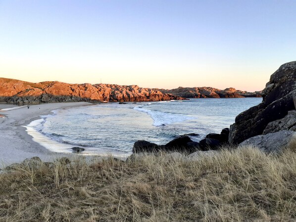 Una playa costera con acantilados rocosos y una orilla arenosa.