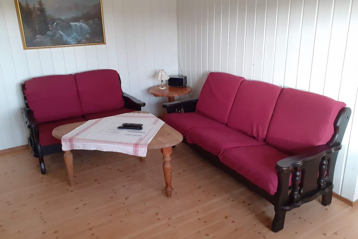 A living room with a red sofa, a wooden coffee table, and a painting on the wall.