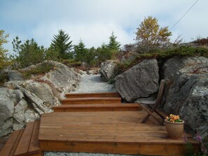 A wooden staircase leading up a rocky path surrounded by trees and a potted plant. - Skudenes Camping (Karmoy)