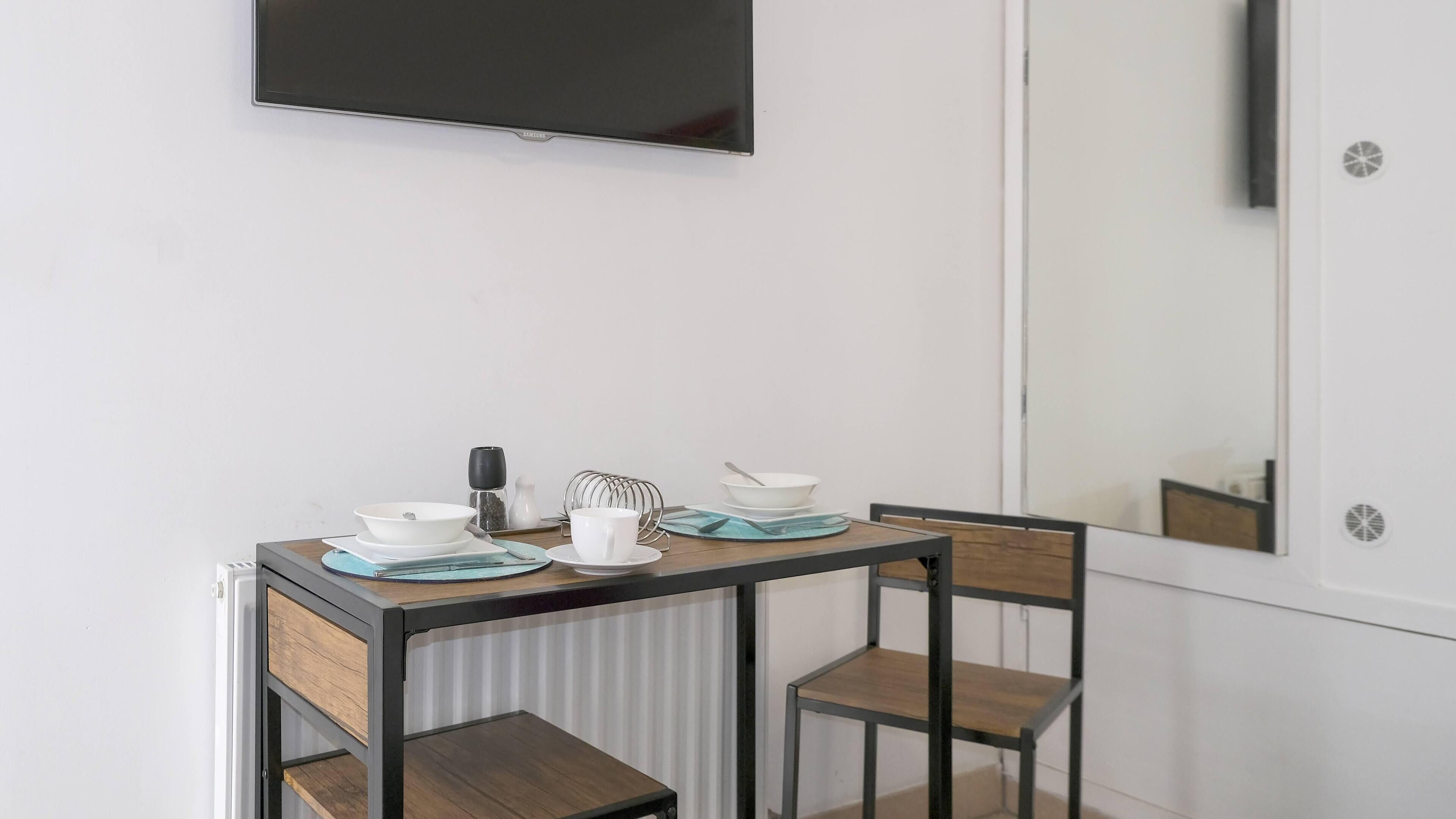 Un petit coin repas avec une table, des chaises et un téléviseur fixé au mur.