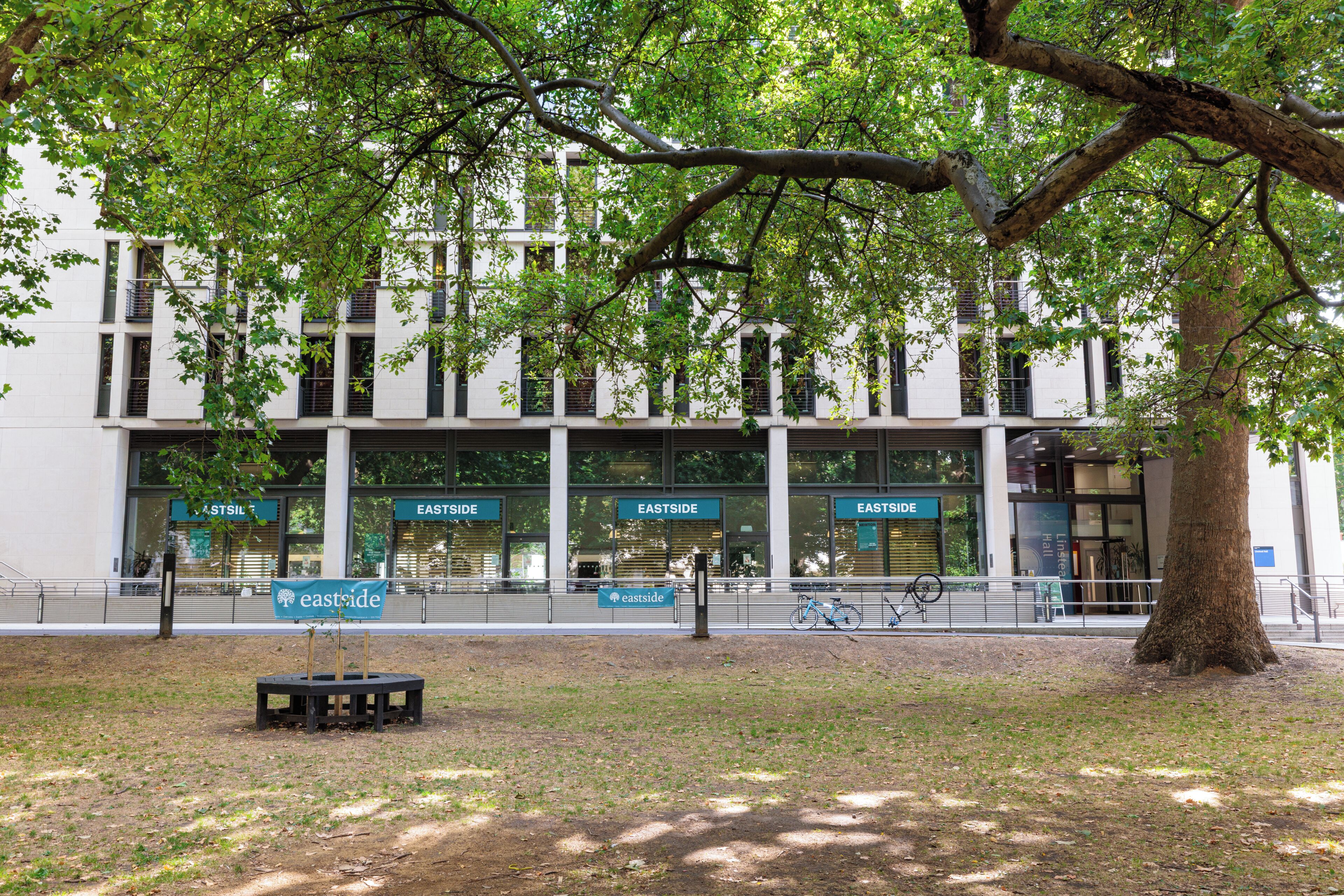 A building with multiple 'EASTSIDE' signs, a bench, and a bicycle.