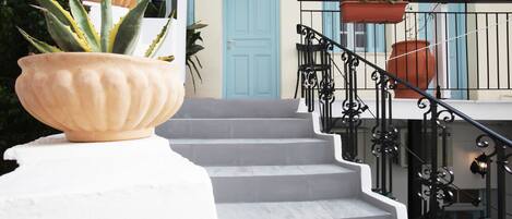 A staircase with a white base and black railing, leading to a blue door.