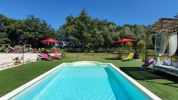 Een buitenzwembad, parasols bij het zwembad en ligstoelen