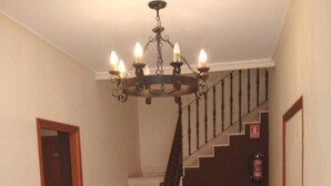 Un pasillo con una escalera, una araña y un extintor.