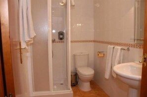 A bathroom with a shower, toilet, and sink. - Hostal Don Juan (El Coronil)