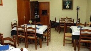 Un comedor con mesas y sillas de madera, un armario de madera y un cuadro en la pared.