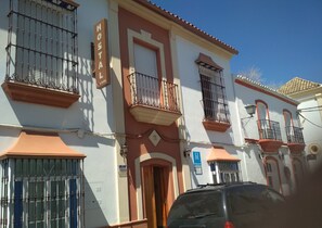 A building with a sign reading "HOSTAL D. N. JUAREZ" and a blue sign indicating a hotel. - Hostal Don Juan (El Coronil)