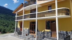 A multi-story building with balconies, stone steps, and a mountainous backdrop. - Hilltop Mestia (Mestia)