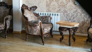 A room with ornate wooden furniture, including a chair and a table, against a patterned wallpaper backdrop. - Hilltop Mestia (Mestia)