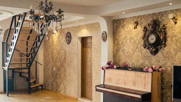 A spacious room with a wooden staircase, a grand piano, and ornate wall decorations. - Hilltop Mestia (Mestia)