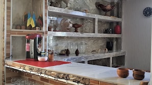 A kitchen with a brick backsplash, shelves with decorative items, a clock on the wall, and a coffee machine. - Hilltop Mestia (Mestia)