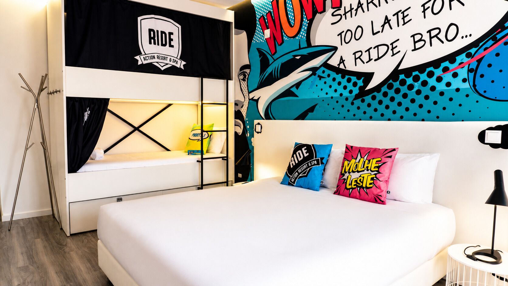 A bed with a white mattress, a black headboard, and a wall with a 'Ride' sign and a shark graphic.