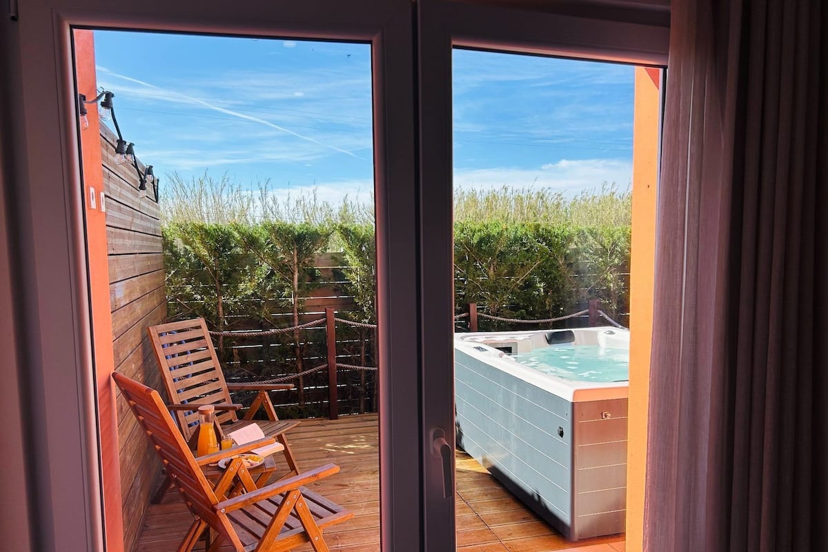 A wooden deck with lounge chairs and a hot tub.