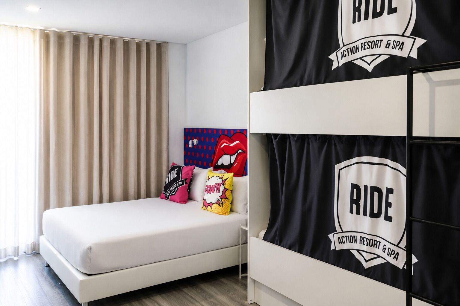 Una habitació d'hotel amb un llit, un capçal amb un dibuix, i una paret amb un logotip.