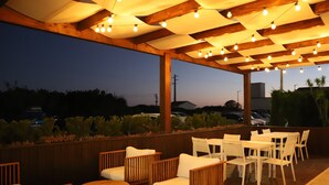 Un espacio al aire libre con mobiliario de madera y luces colgantes.