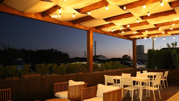 Un espacio al aire libre con mobiliario de madera y luces colgantes.