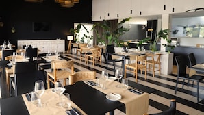 Un restaurante moderno con suelo de cuadros blancos y negros, mesas y sillas de madera.