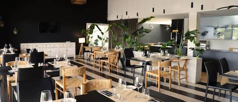 A modern restaurant with black and white checkered flooring, wooden tables, and chairs.