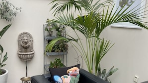 A cozy seating area with a black leather sofa, a decorative chandelier, and a variety of plants. - Stephansens Hotel (Randers)