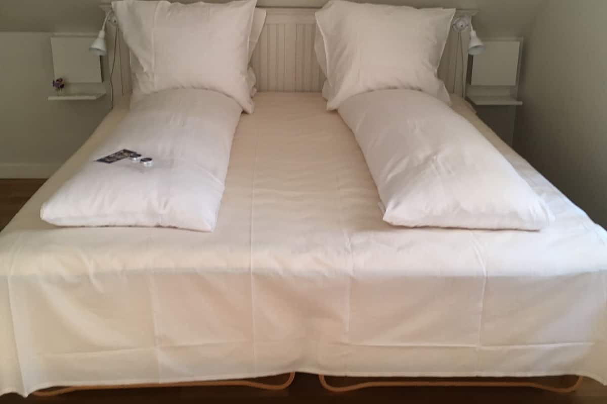 A single bed with white bedding in a room with a sloped ceiling.