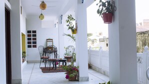 Uma área externa coberta com uma mesa e cadeiras, plantas em vasos e plantas pendentes.