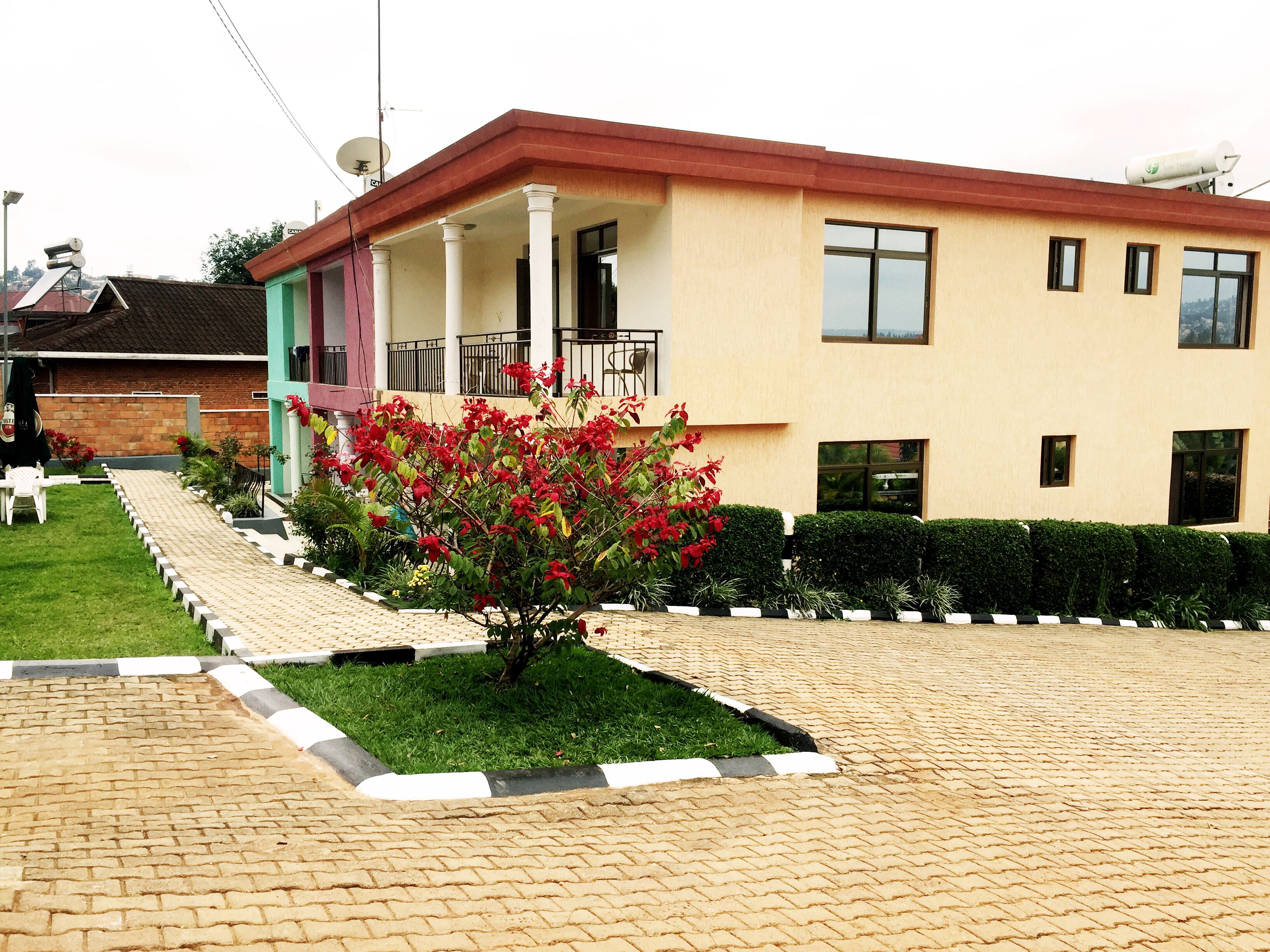 A two-story building with a red roof, a covered porch, and a small garden with red flowers.