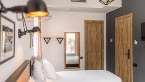 A modern bedroom with a bed, a bedside lamp, a mirror, and wooden doors. - Timber Boutique Hotel (Tbilisi)
