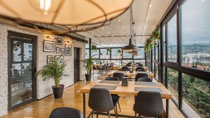 A modern dining area with long tables, black chairs, and potted plants. - Timber Boutique Hotel (Tbilisi)