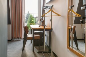 Una habitación con un escritorio de madera, una silla, una lámpara colgante y un espejo en la pared.