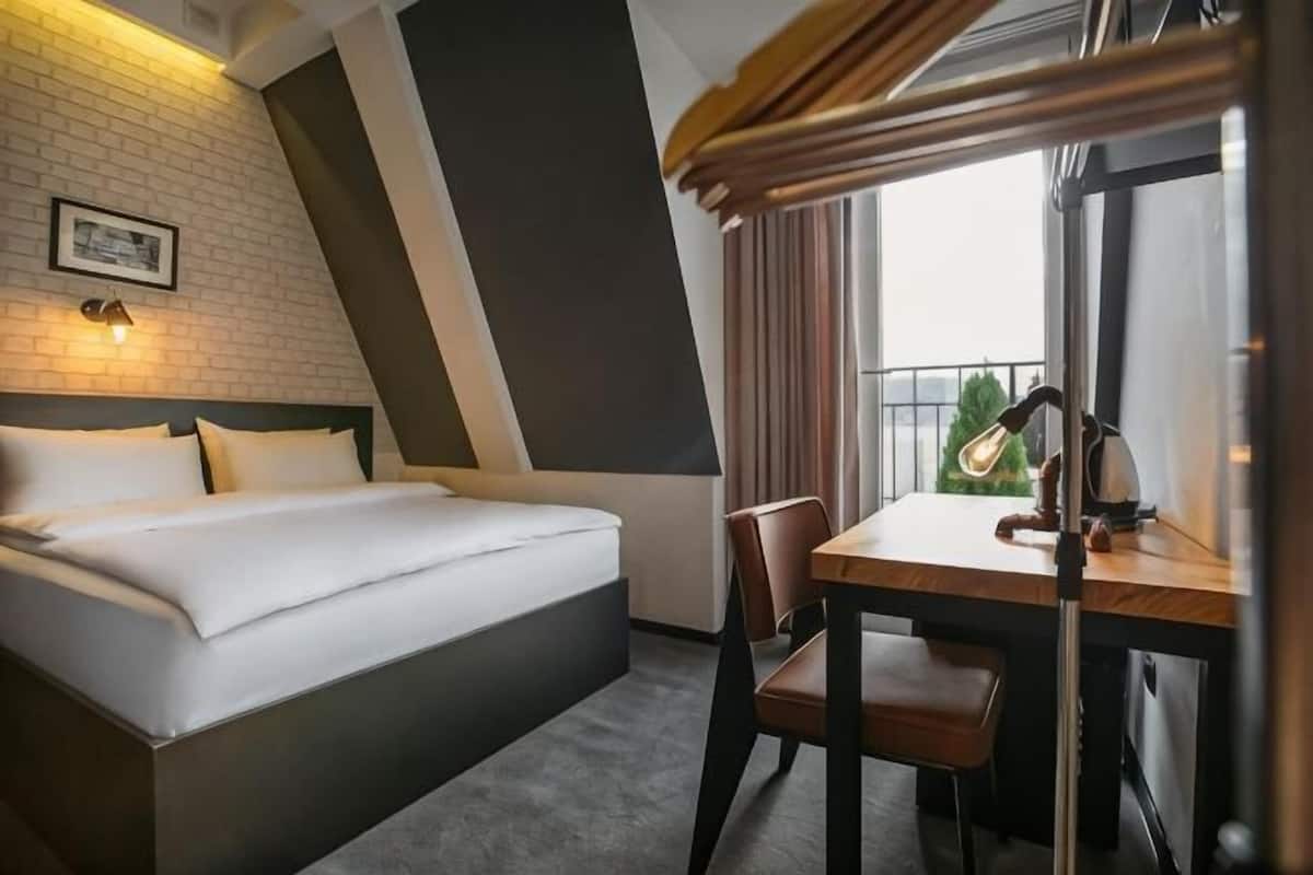 A hotel room with a bed, a desk, and a chair.